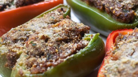 red and green bell pepper half's stuffed with crawfish on a green trimmed platter