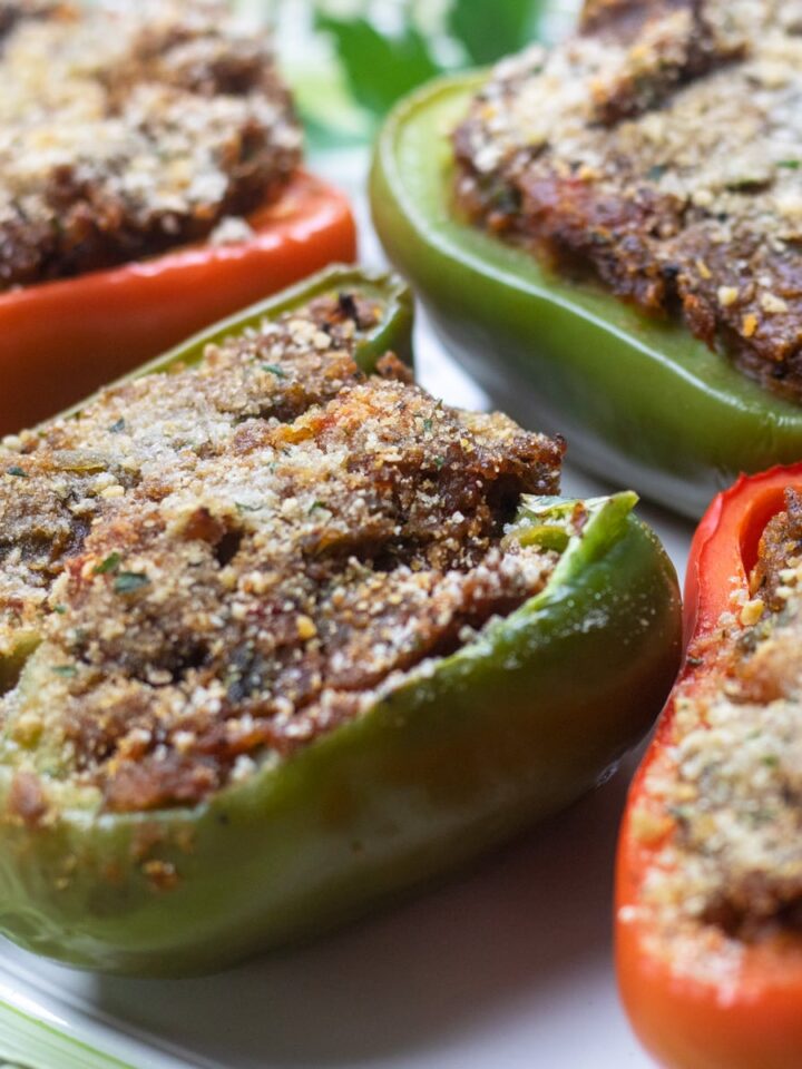 red and green bell pepper half's stuffed with crawfish on a green trimmed platter