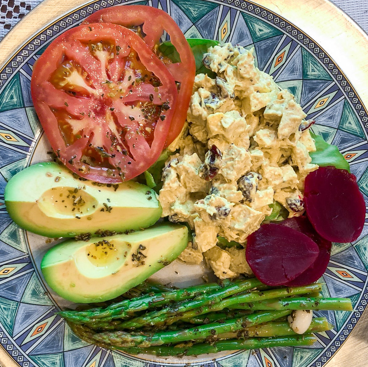 chicken salad, beets, asparagus, avacado and tomatoes on a plate with green trim