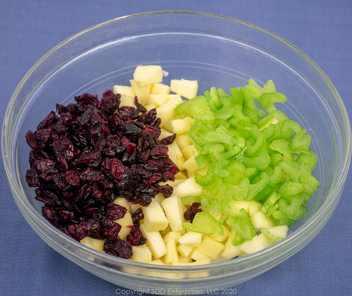 dried cranberries, diced apples and sliced celery in a clear bowl