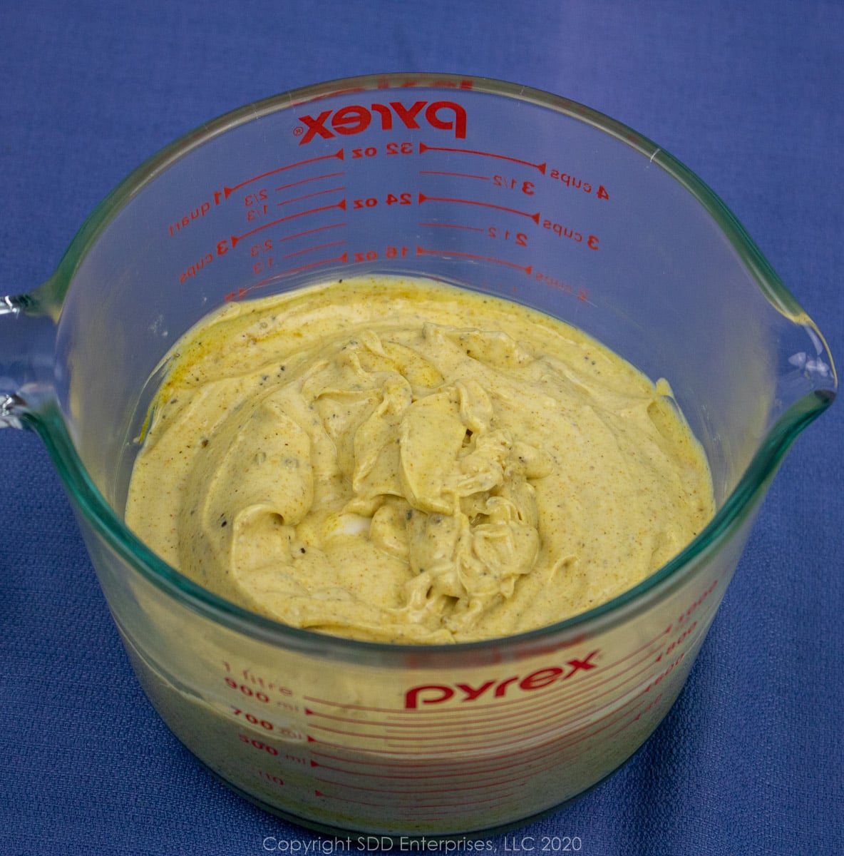 lemon curry dressing in a measuring cup