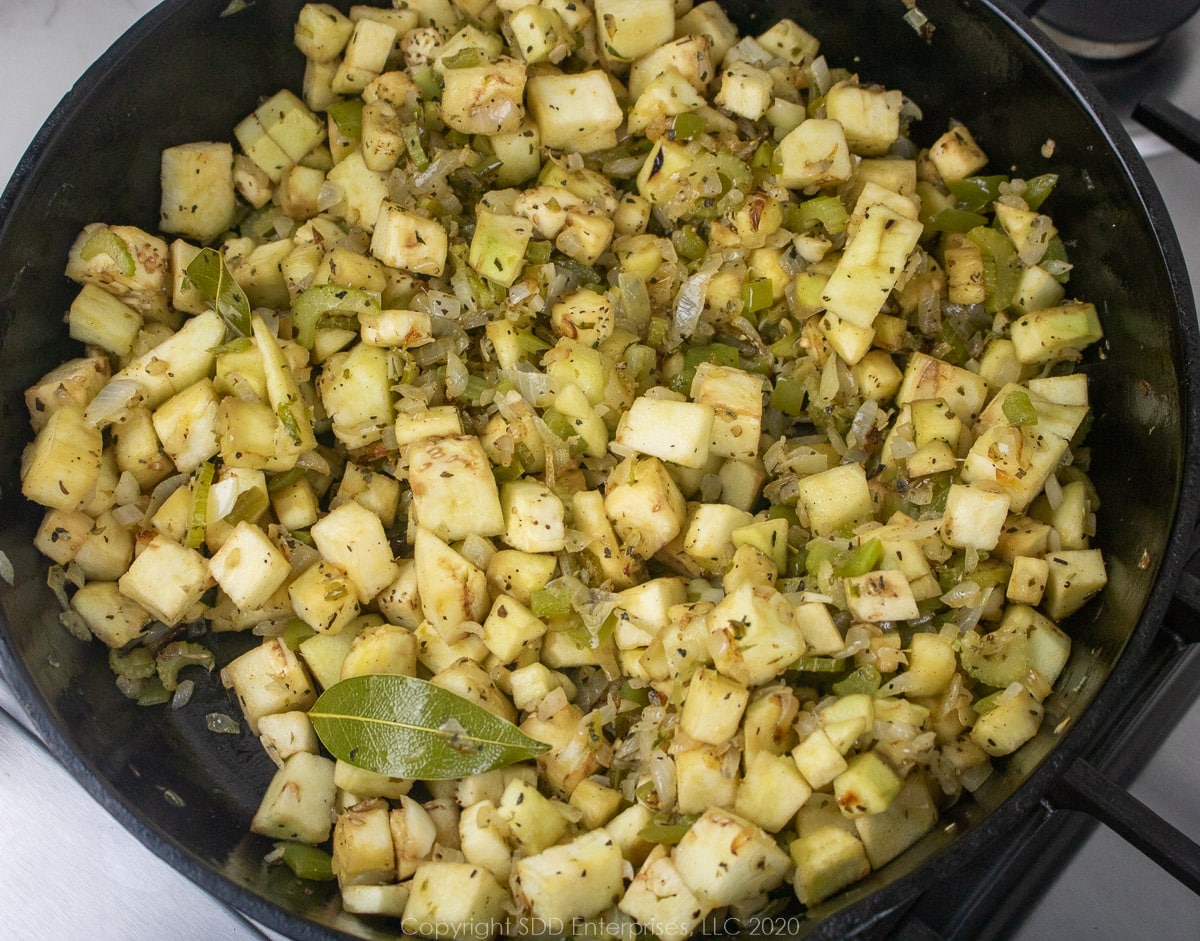 cubed eggplant added to sauteeing vegetables in cast iron pan