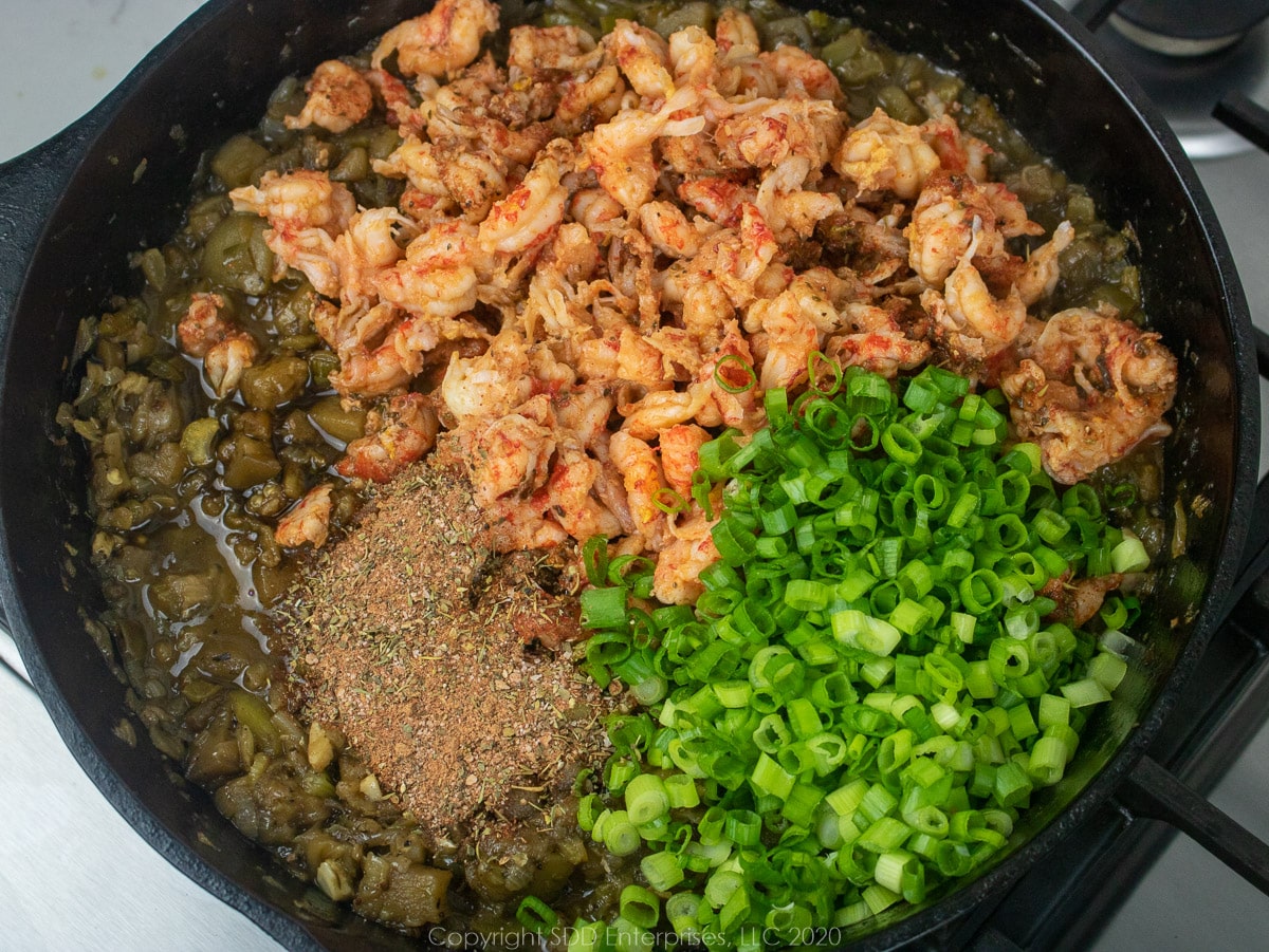 crawfish and green onions in a cast iron pan with sauteed vegetables