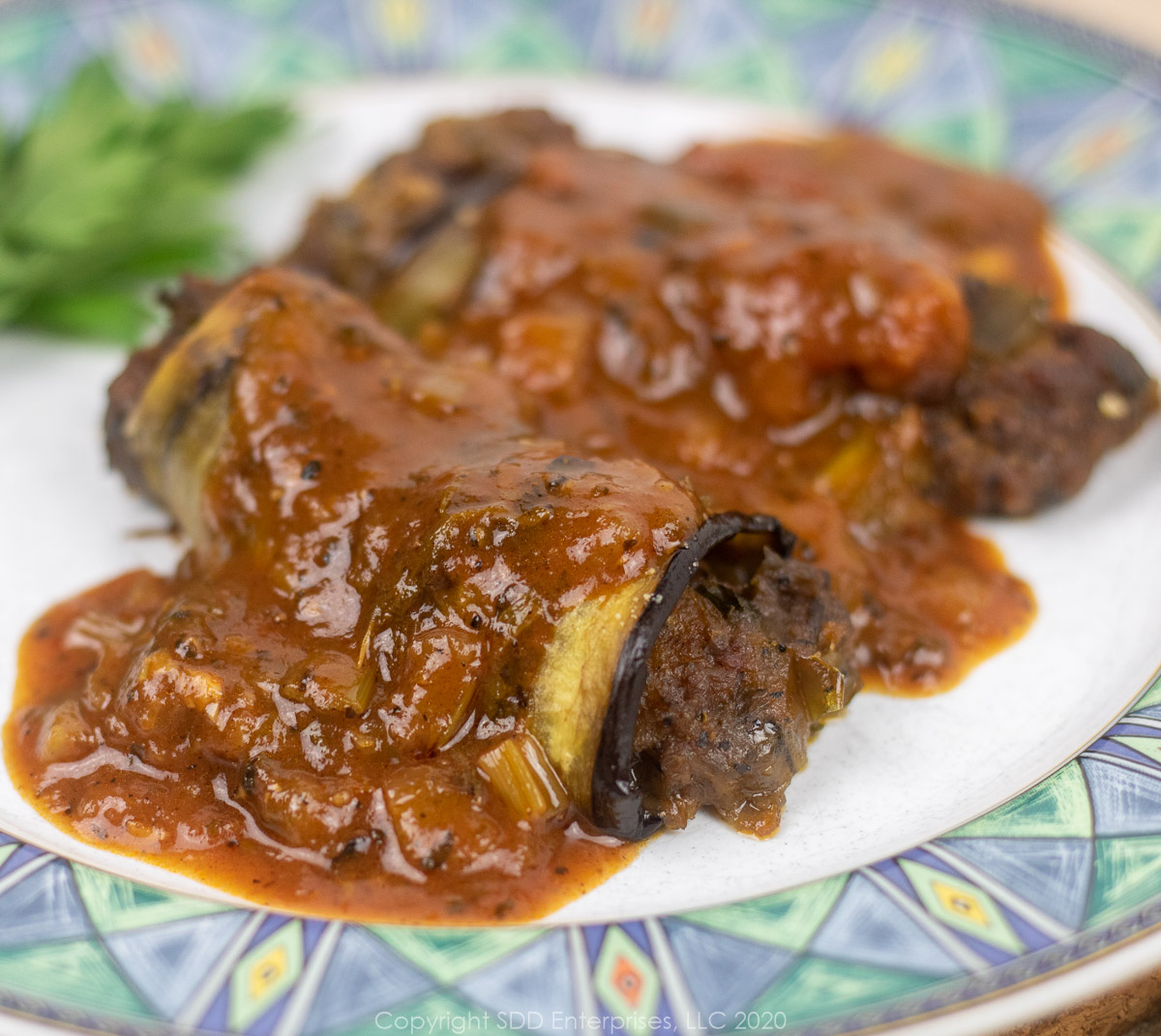 crawfish eggplant rollatini with sauce creole on a plate with parsley garnish