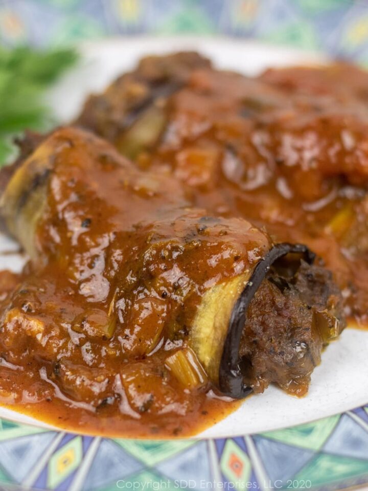 crawfish eggplant rollatini with sauce creole on a plate with parsley garnish