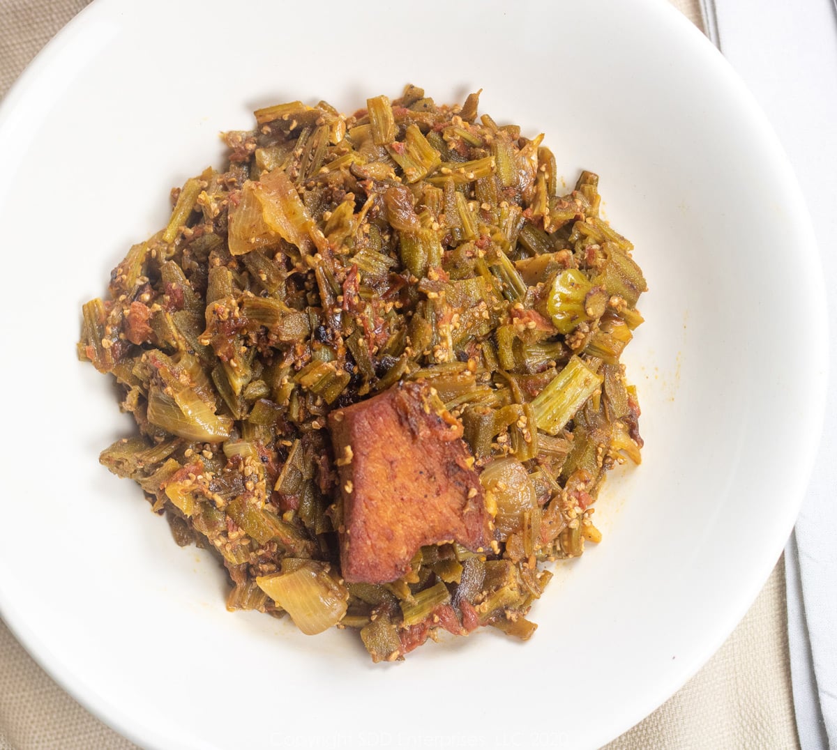 stewed okra with ham and tomatoes in a white bowl