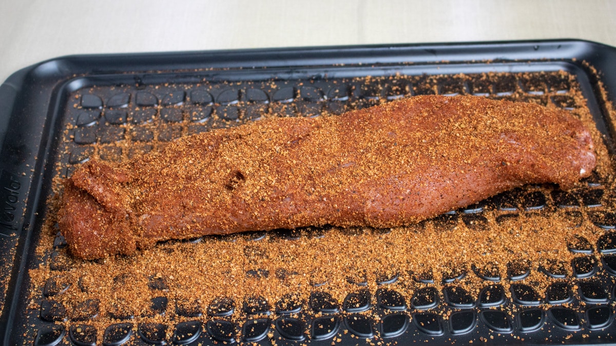 pork tenderloin resting in dry Cajun rub on a prep platter