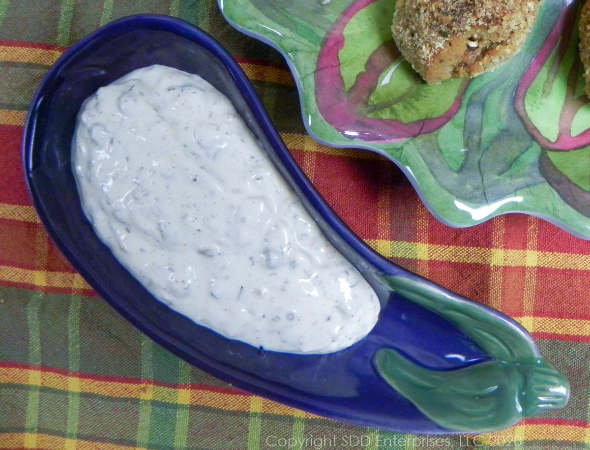 creole tartar sauce in a purple bowl on a plaid background  next to a plate of stiffed shrimp