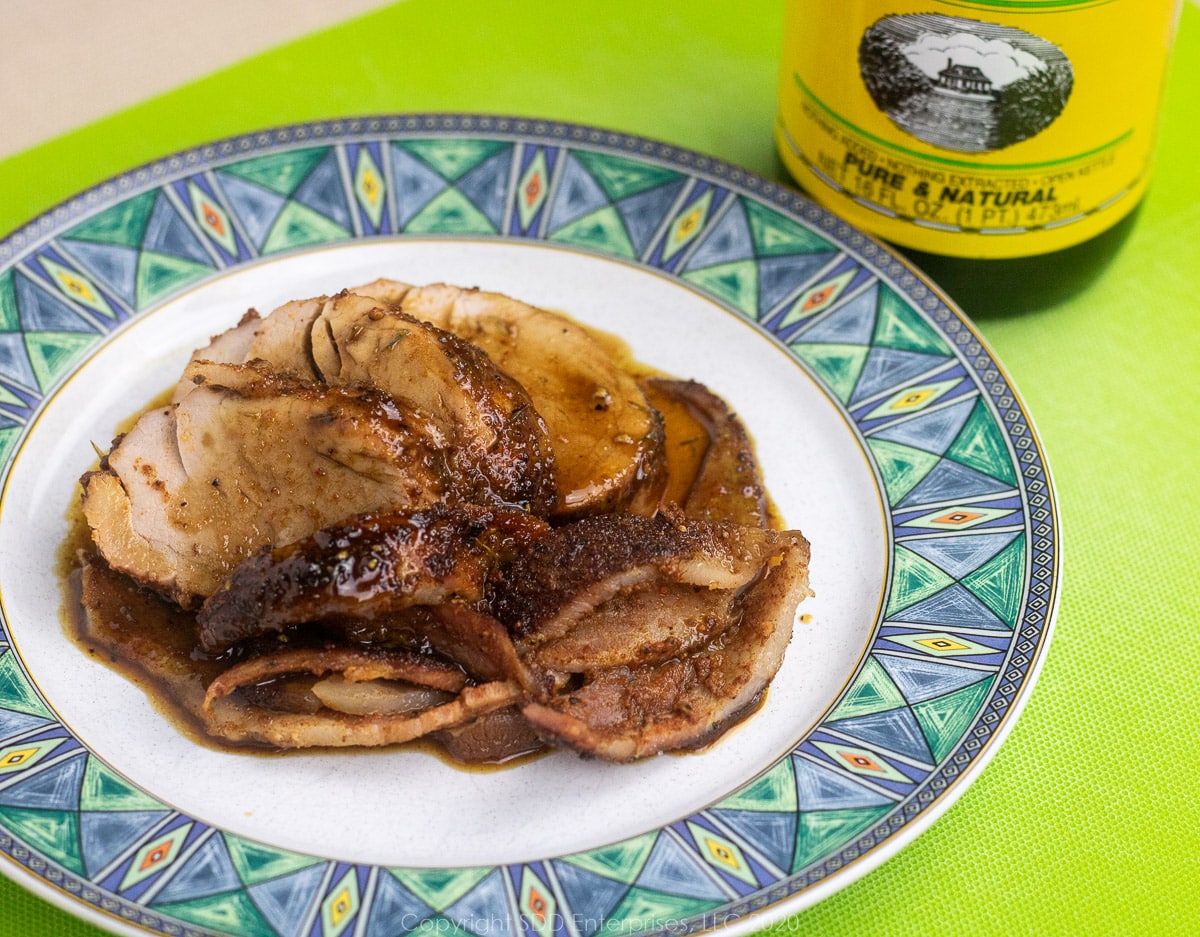 pork tenderloin with cane syrup sauce on a white plate with blue-green trim