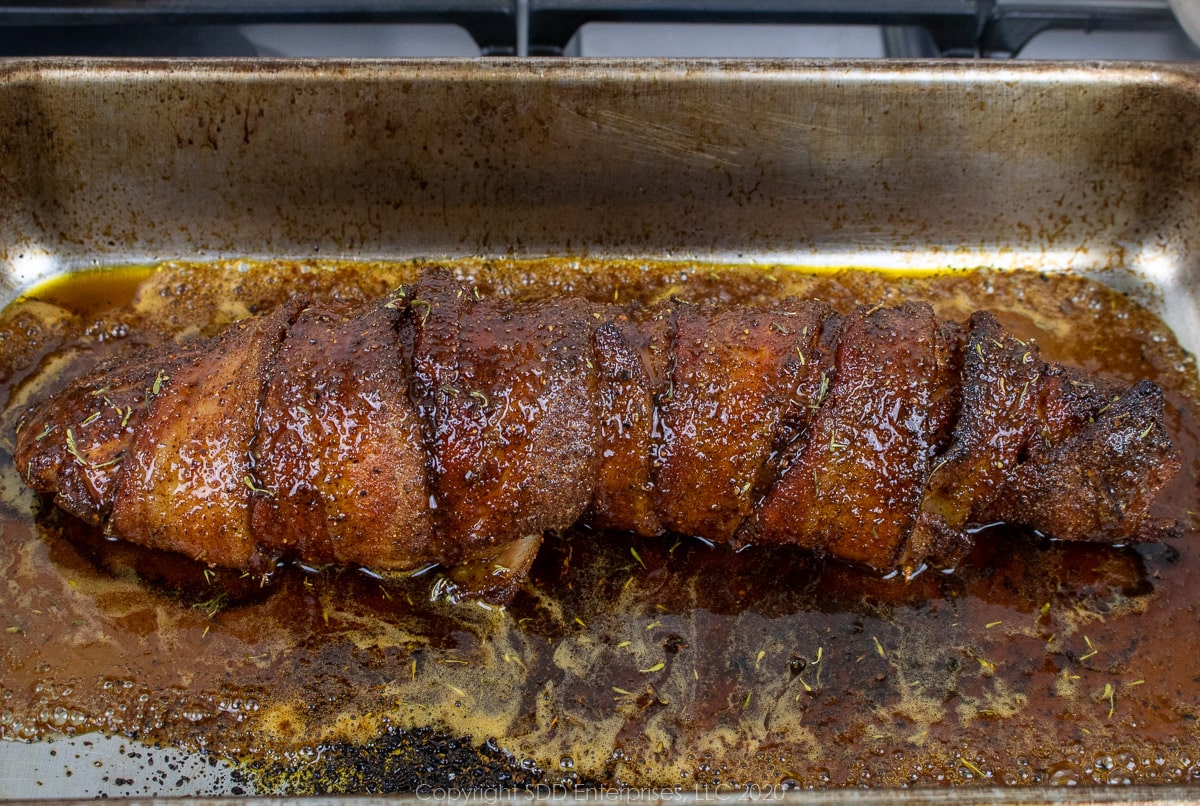 wrapped pork tenderloin with vane syrup sauce in a baking pan 