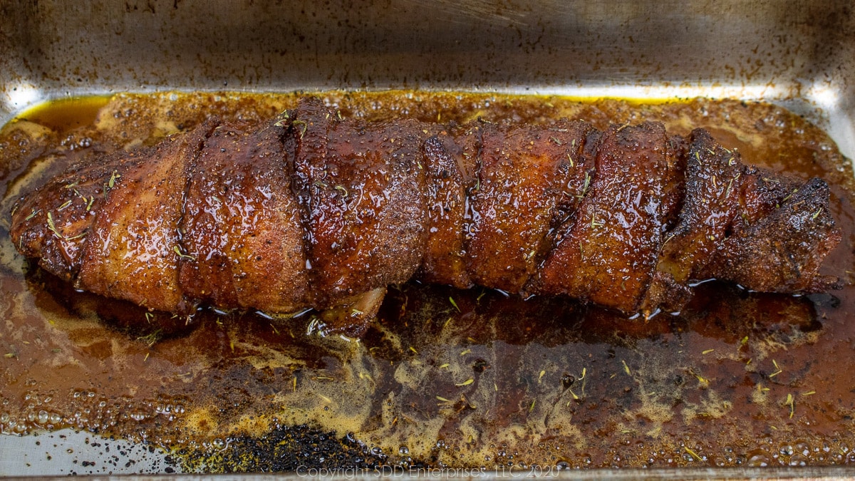 bacon wrapped pork tenderloin with cane syrup sauce in a baking pan
