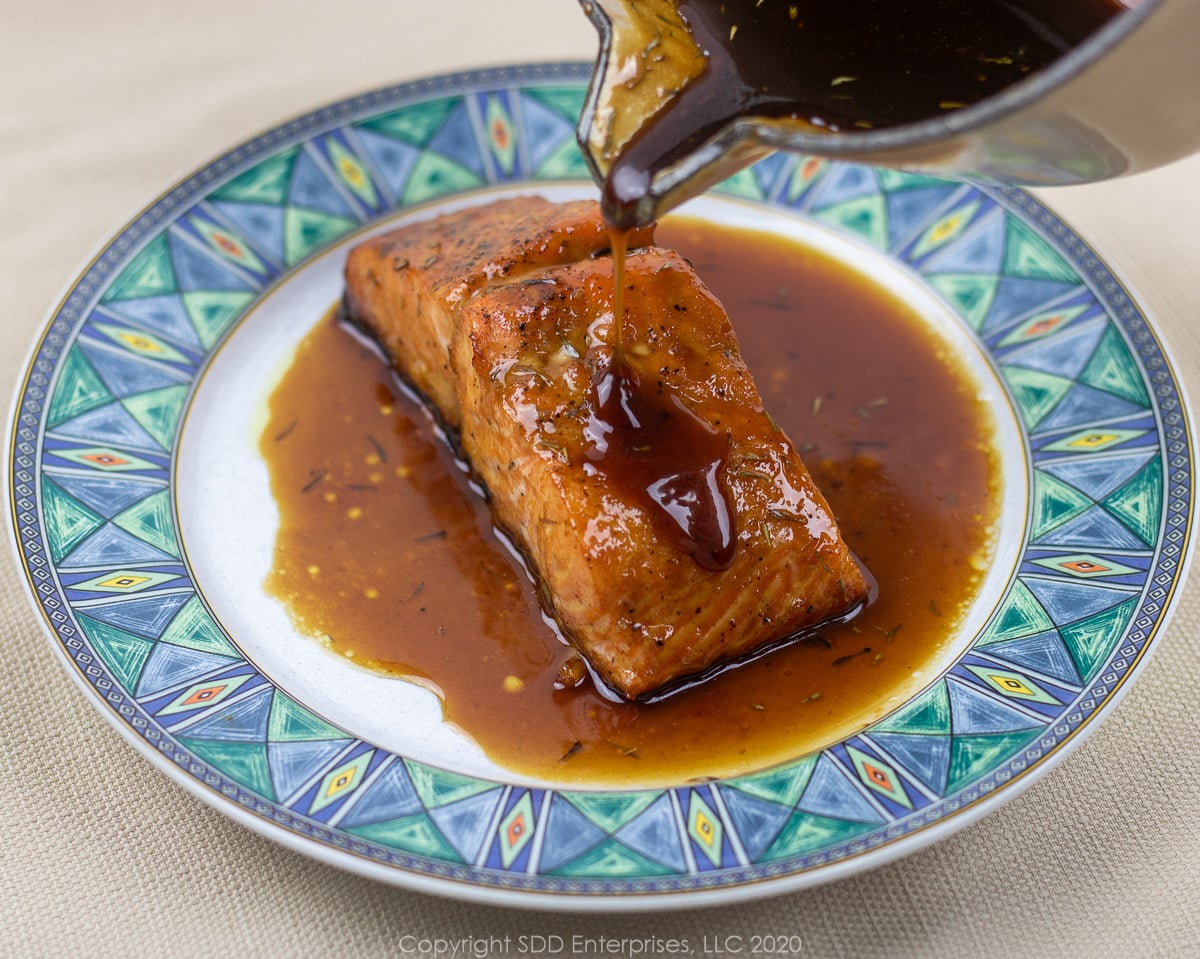 pouring cane syrup sauce onto a baked salmon fillet