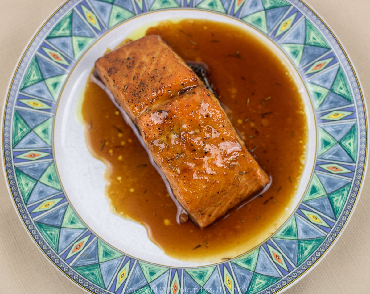 roasted salmon with cane syrup sauce on a white plate with blue-green trim