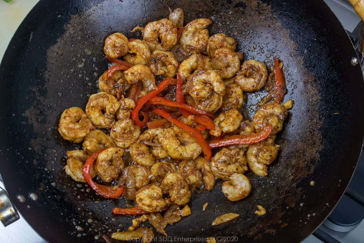 shrimp sauteing with onions and peppers in a wok