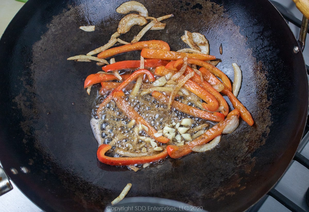 garlic with onions and peppers sauteing in a wok
