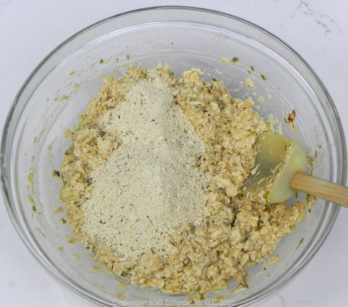 breadcrumbs added to crab meat stuffing in a glass bowl