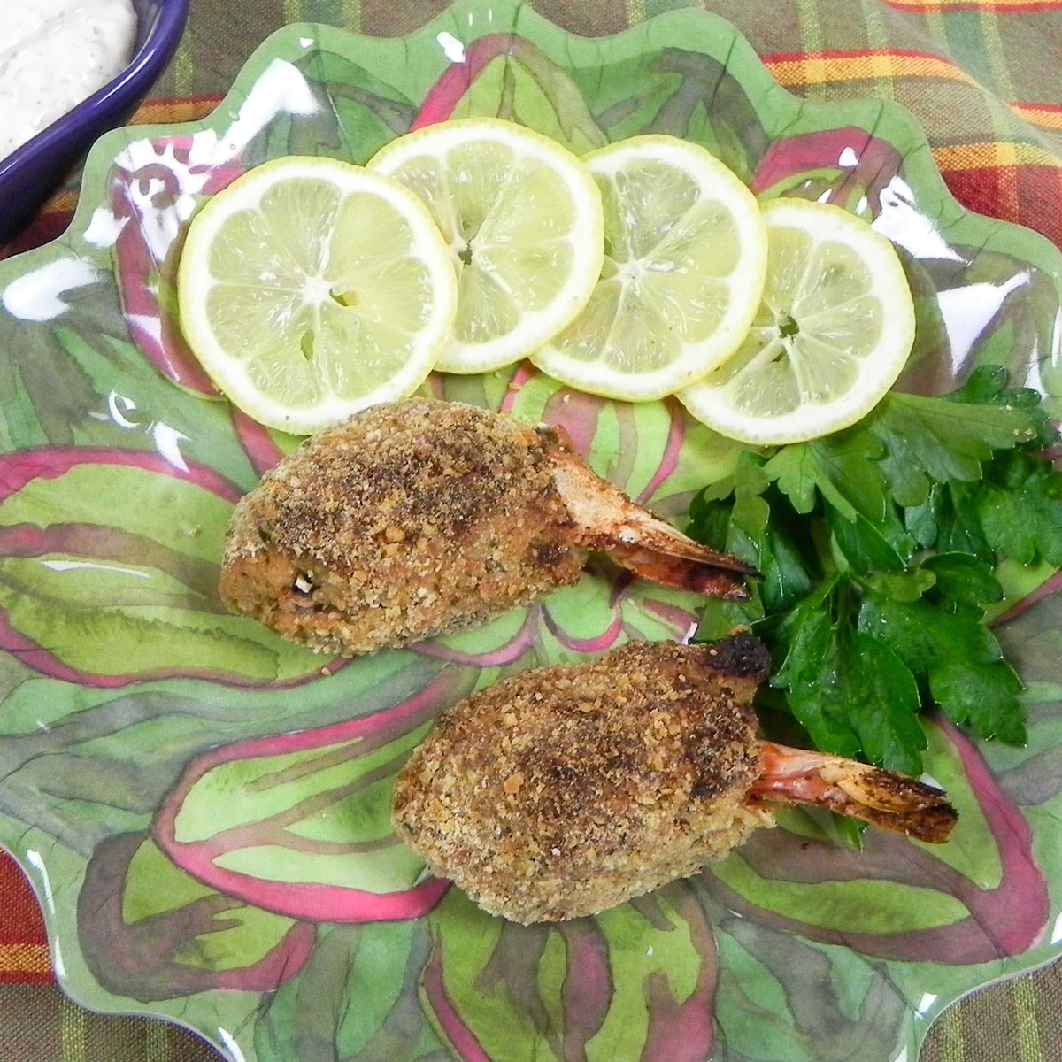 two baked stuffed shrimp on a green plate with lemon and parsley garnish