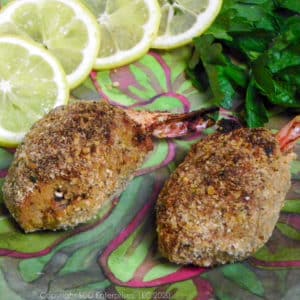two baked stuffed shrimp on a green plate with lemon and parsley garnish