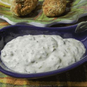 creole tartar sauce in a purple dish with stuffed shrimp on a green plate in the back ground