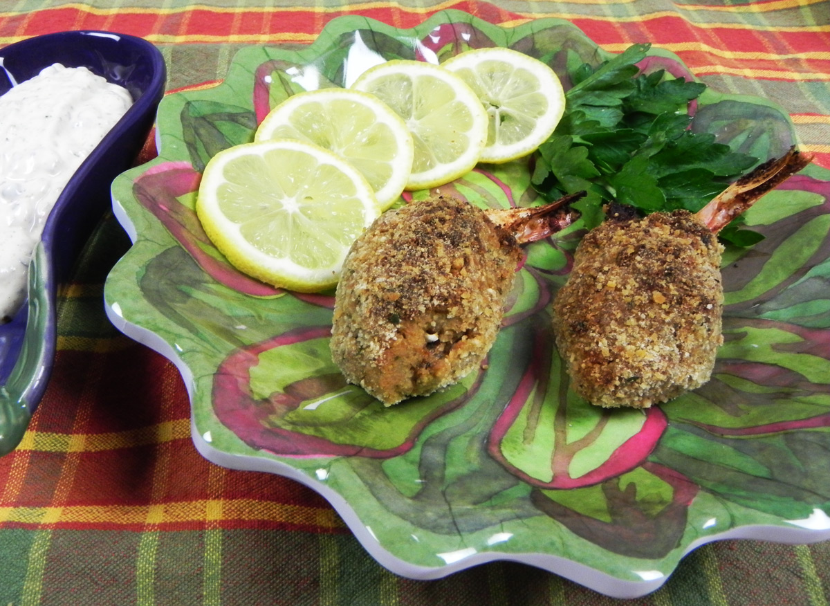 two crab meat stuffed shrimp on a green plate with lemon and parsley garnish and creole tartar sauce