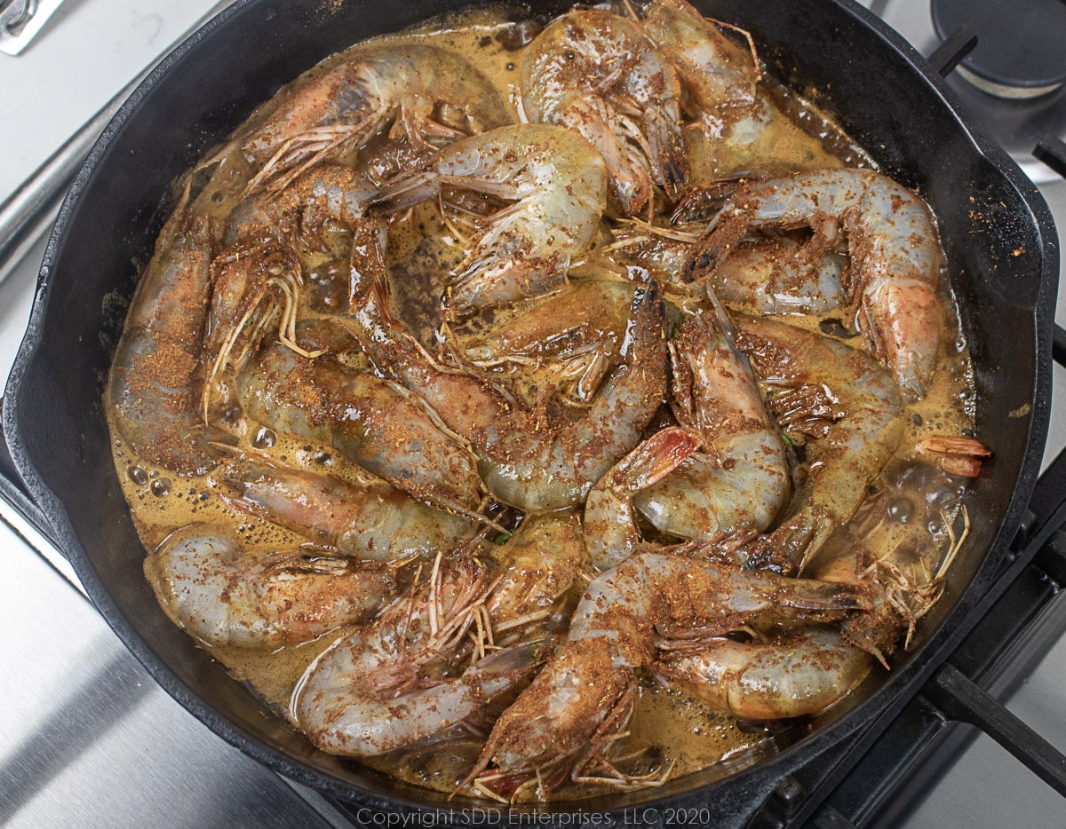 shrimp sauteeing in sauce in a cast iron skillet for barbecued shrimp