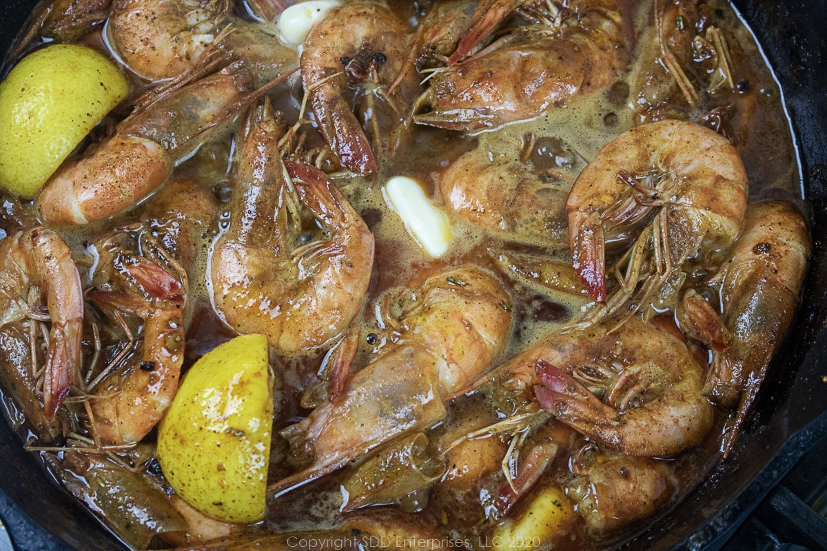 butter melting in barbecued shrimp in a cast iron skillet