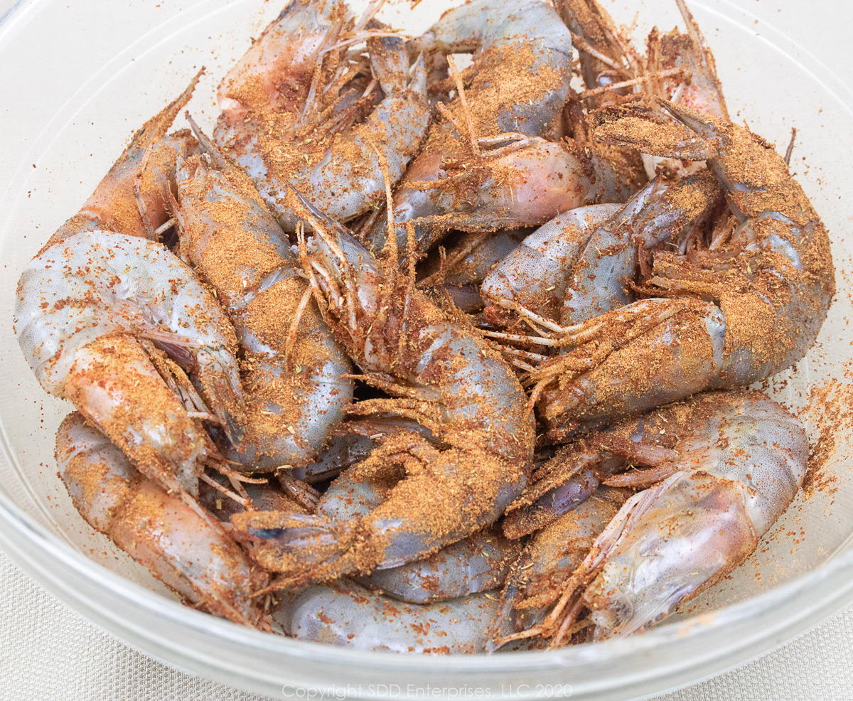 large shrimp in the shell with creole seasoning in a glass bowl