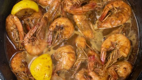 bbq shrimp in a cast iron skillet with lemon wedges