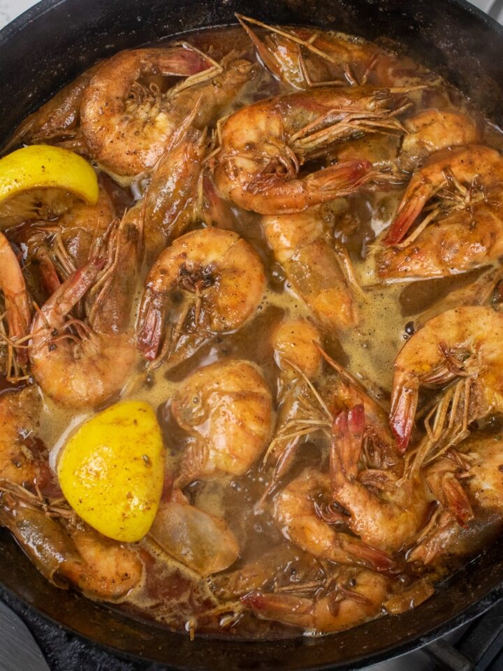 bbq shrimp in a cast iron skillet with lemon wedges