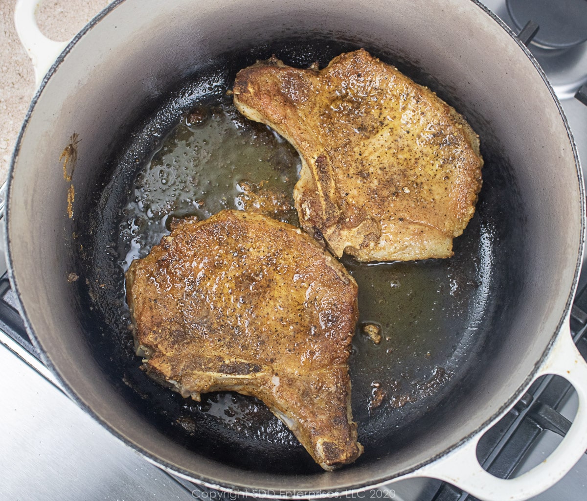 bone-in pork chops searing in a dutch oven