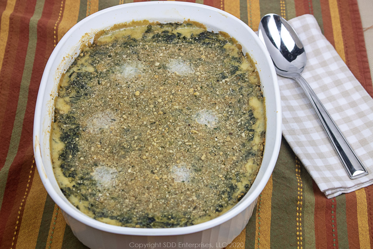 spinach madeleine in a white casserole dish with spoon on a napkin