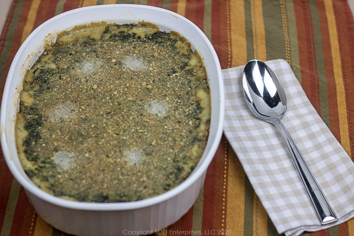 spinach Madeleine in a white casserole with a spoon on the side