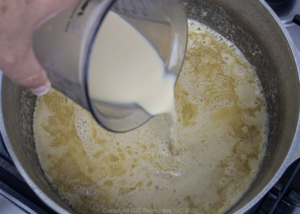 liquids being added to roux in a dutch oven