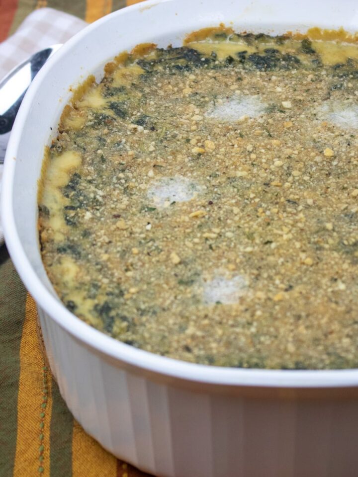 spinach madeleine in a white casserole dish with a spoon on the side