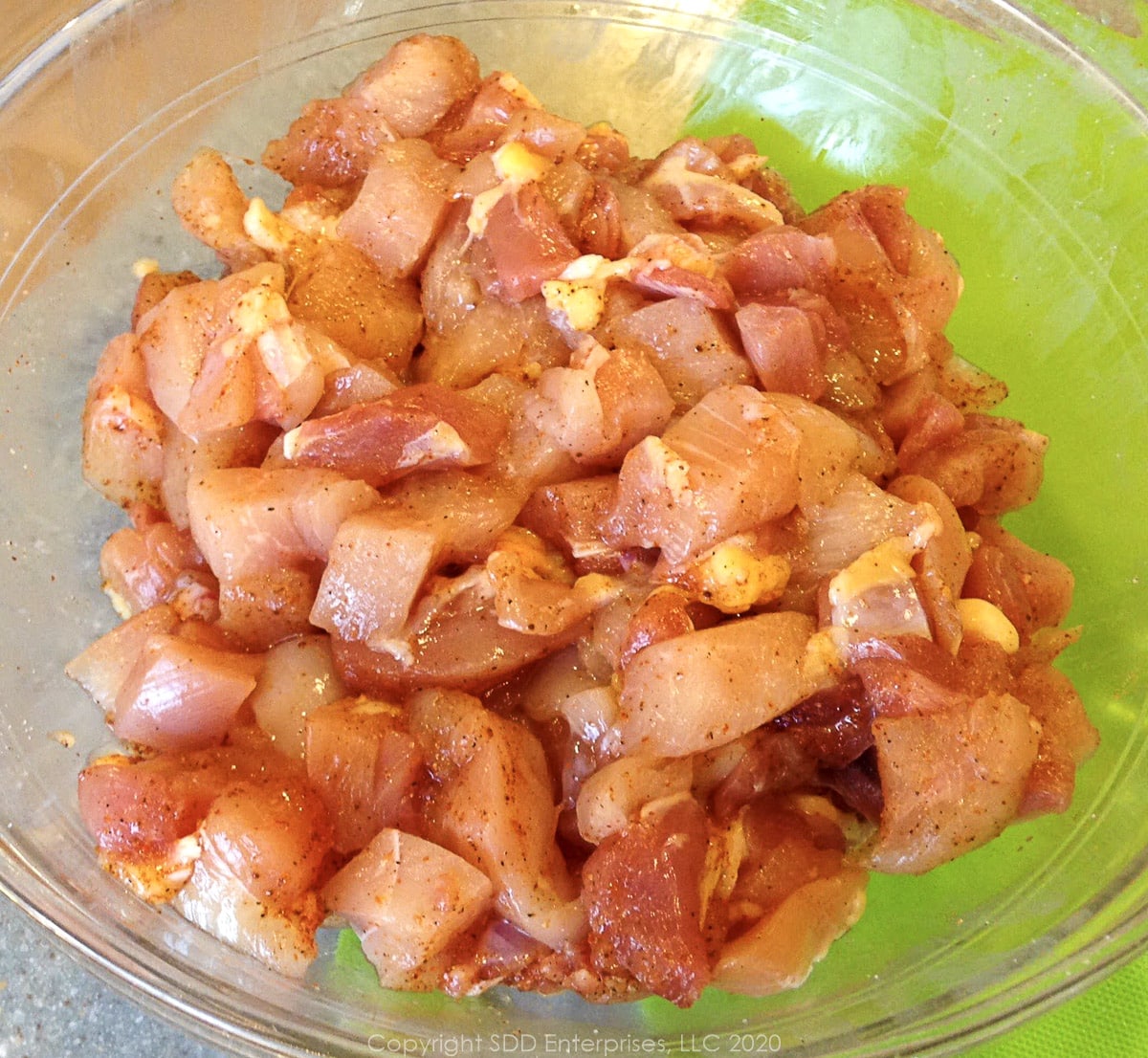 seasoned cut up uncooked chicken in a glass bowl