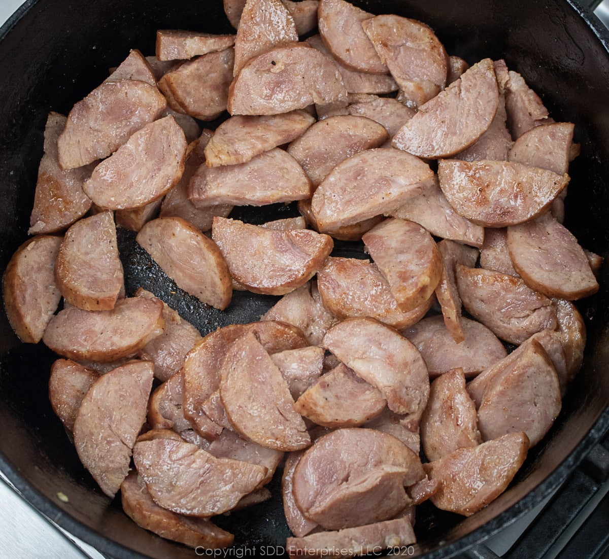 andouille sausage frying in a dutch oven