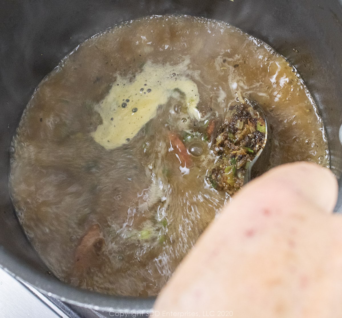 stirring vegetables into a stock in a stockpot