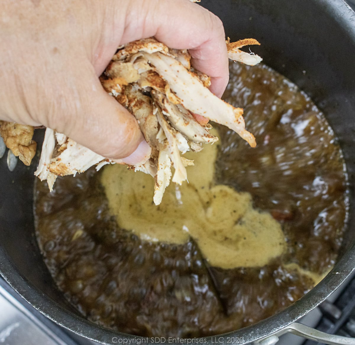 chicken being added to the stock for chicken andouille gumbo