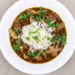 chicken and andouille gumbo with rice and garnish in a white bowl