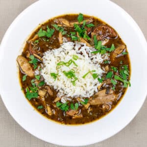 chicken and andouille gumbo with rice and garnish in a white bowl