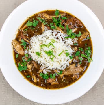 chicken and andouille gumbo with rice and garnish in a white bowl