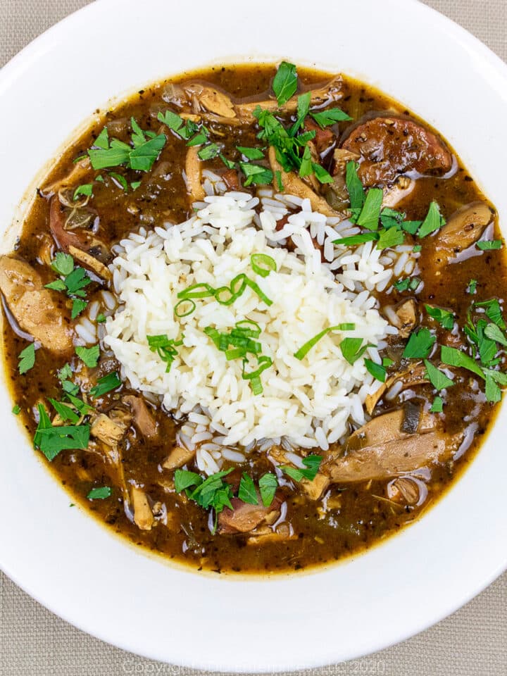 chicken and andouille gumbo with rice and garnish in a white bowl