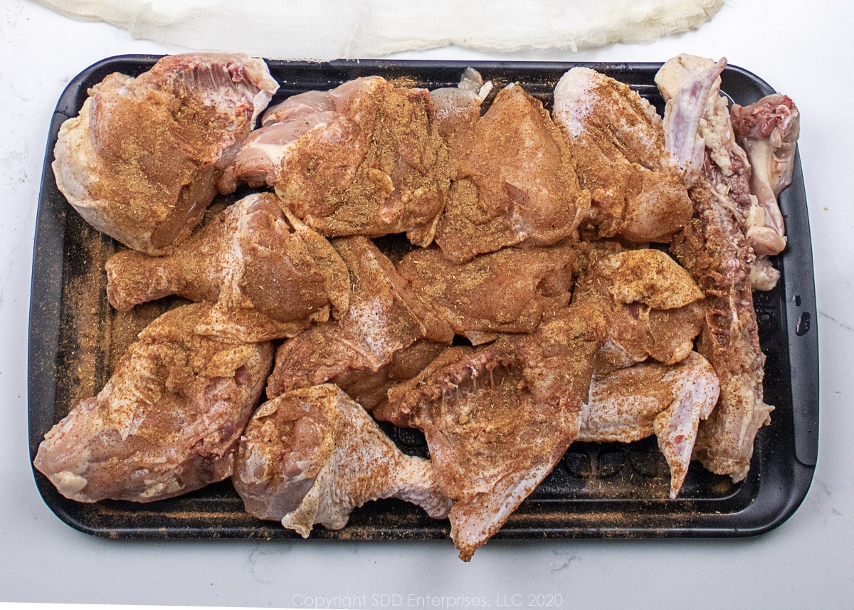 cut up chicken with seasoning on a prep board