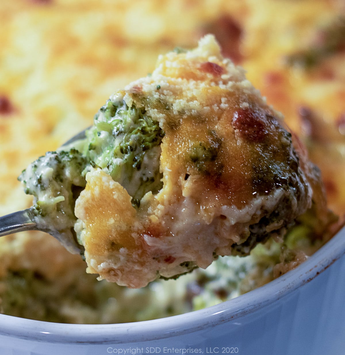 a spoonful of broccoli casserole in a white baking dish