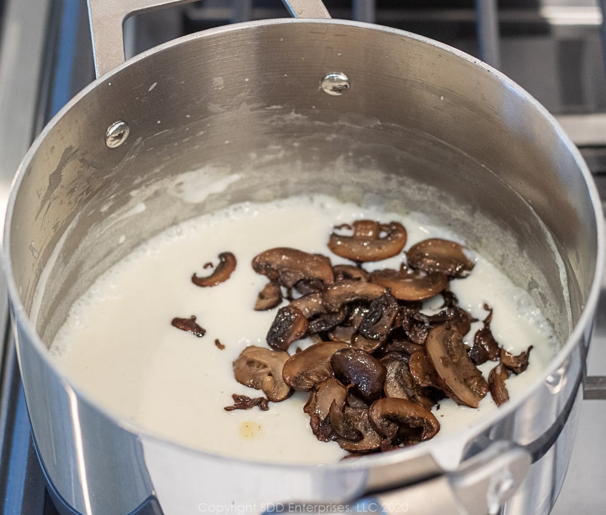 sautéed mushrooms added to bechamel sauce in a sauce pan