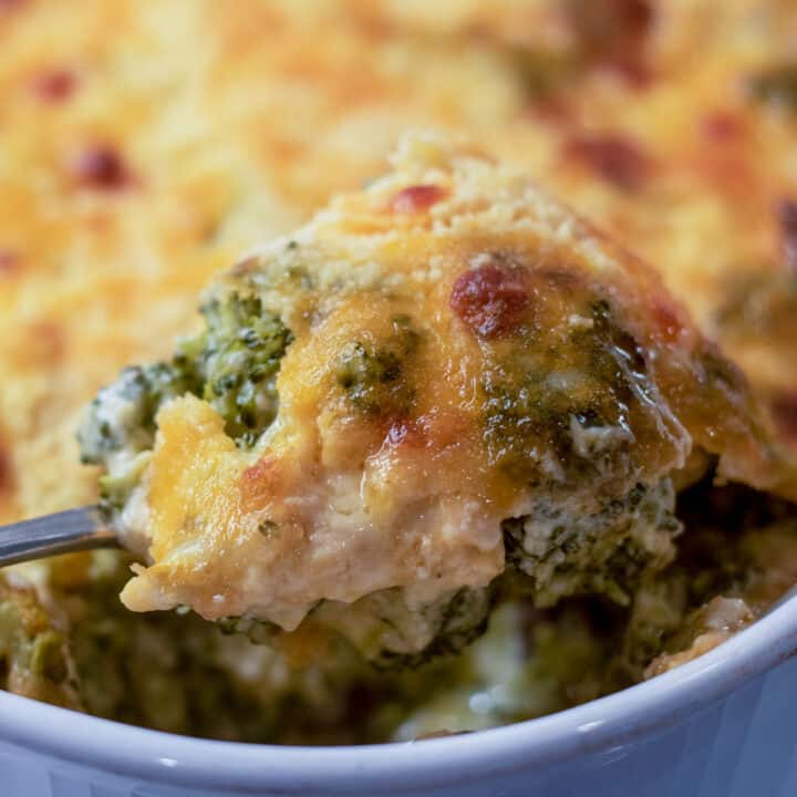 broccoli cheese casserole with a serving spoon in a white baking dish