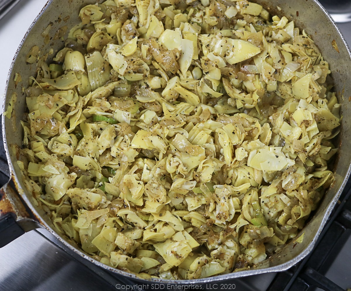 artichoke hearts added to sautéing vegetables in a frying pan