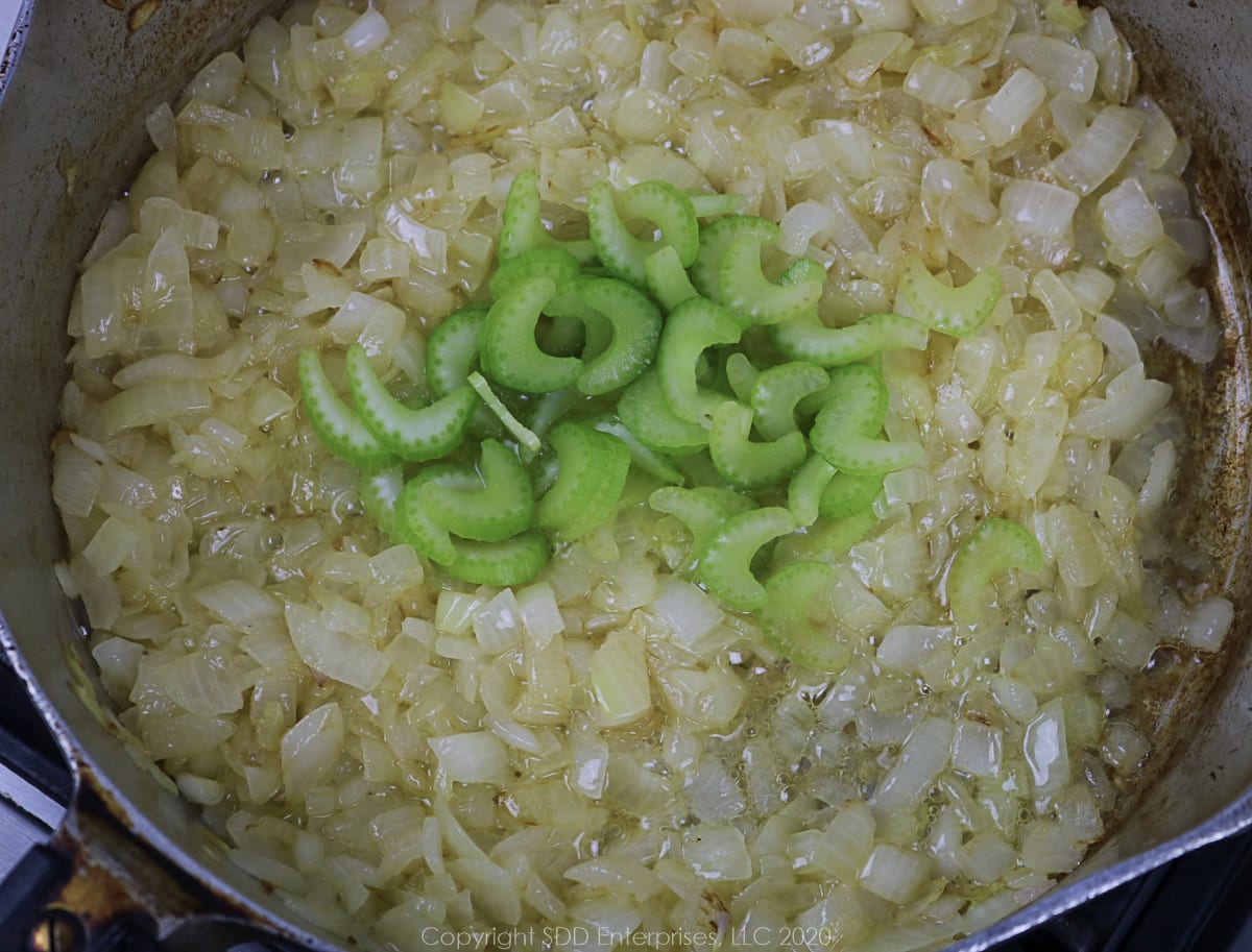 celery and yellow onions sautéing in butter in a frying pan