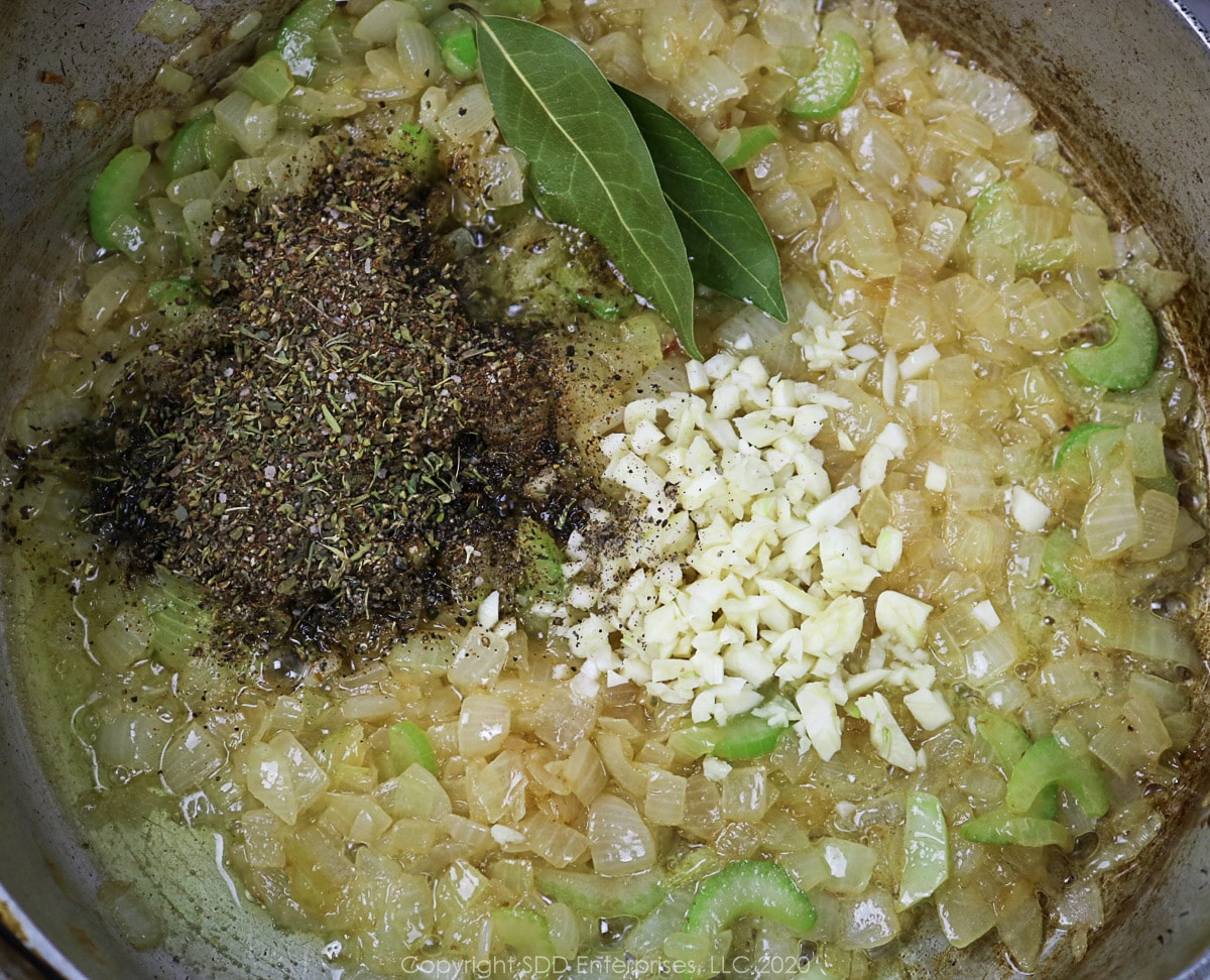 herbs and spices and garlic added to sautéing vegetables in a frying pan