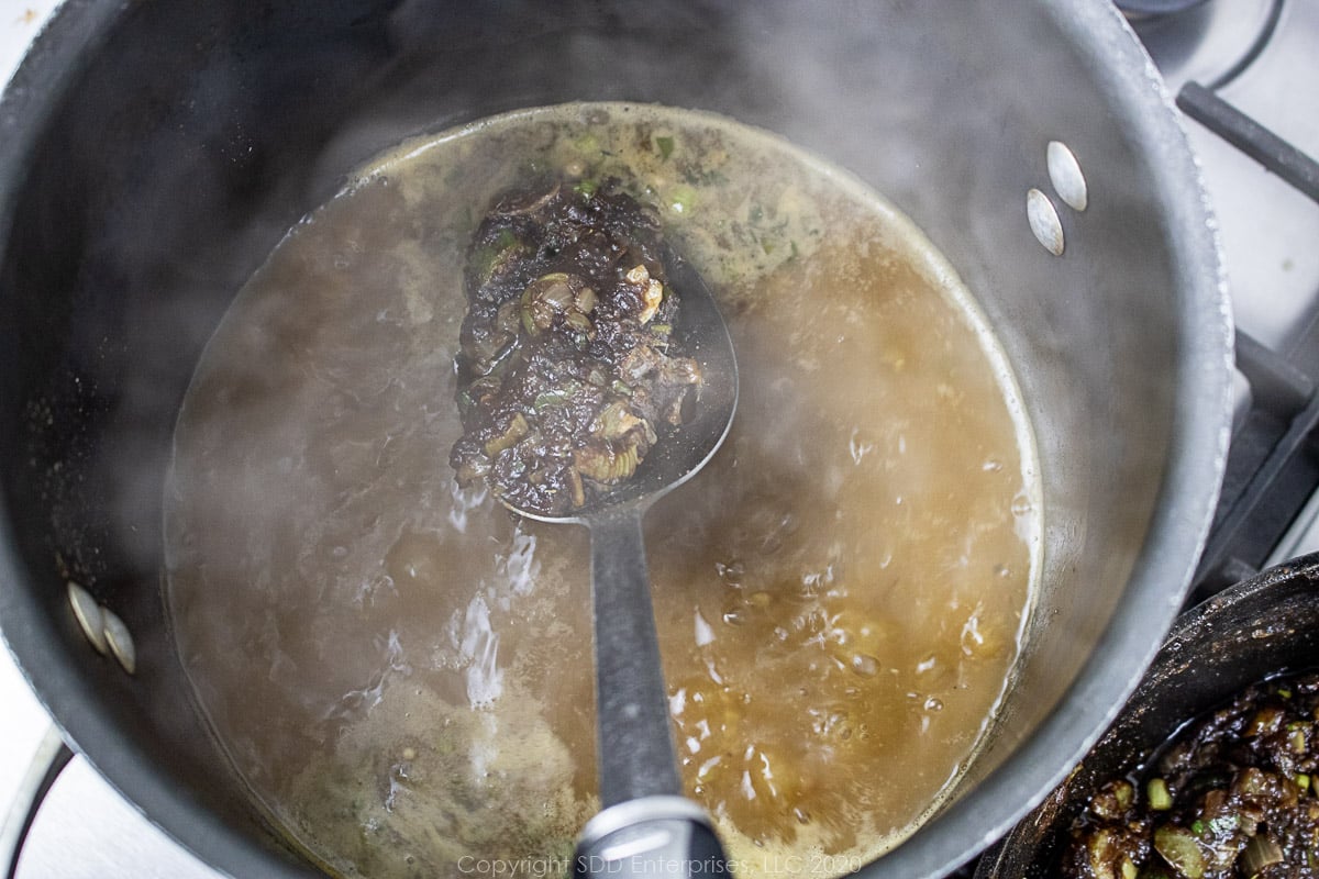 stirring roux mixture into seafood stock in a stockpot